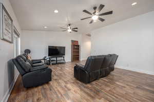 Living room with lofted ceiling, hardwood / wood-style floors, and ceiling fan