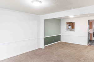 Carpeted spare room featuring a textured ceiling and crown molding