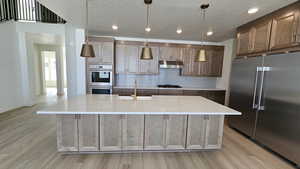 Kitchen featuring an island with sink, stainless steel appliances, and sink