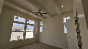 Unfurnished room featuring beamed ceiling, dark hardwood / wood-style floors, and ceiling fan