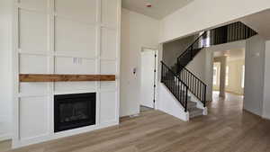 Unfurnished living room with a towering ceiling, a textured ceiling, and light hardwood / wood-style flooring