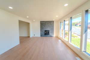 Unfurnished living room with a stone fireplace and light hardwood / wood-style floors