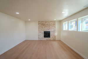 Unfurnished living room with a textured ceiling, a fireplace, and light hardwood / wood-style floors