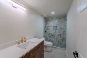 Bathroom featuring toilet, an enclosed shower, vanity, and tile patterned flooring