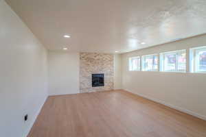 Unfurnished living room with light hardwood / wood-style flooring, a textured ceiling, and a fireplace