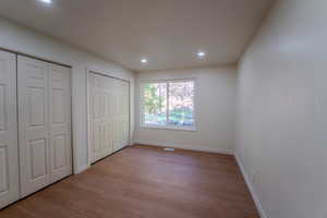 Unfurnished bedroom featuring light hardwood / wood-style floors and two closets