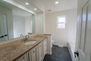 Bathroom featuring vanity, toilet, tile patterned floors, and a bath