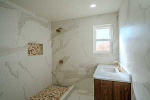 Bathroom featuring vanity, a shower, and tile walls