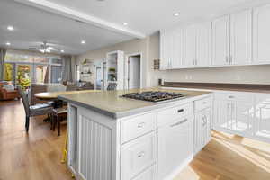 Kitchen featuring white cabinetry, stainless steel gas cooktop, light wood-type flooring, and ceiling fan