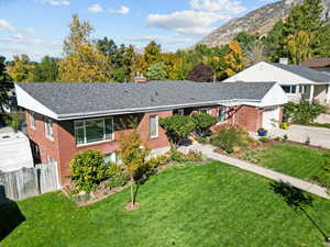 View of front of house featuring a mountain view, a front lawn, and a garage