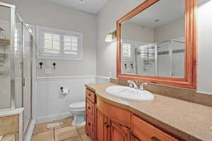 Bathroom featuring a shower with door, vanity, toilet, and tile patterned floors