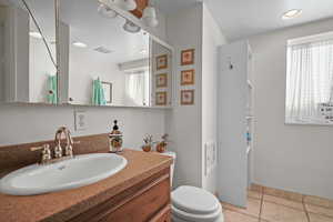 Bathroom featuring toilet, walk in shower, vanity, and tile patterned flooring