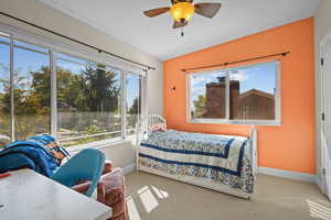 Carpeted bedroom with ceiling fan and multiple windows