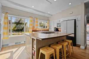 Kitchen featuring light hardwood / wood-style floors, a breakfast bar, backsplash, and white appliances