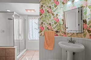 Bathroom with a shower with shower door and tile patterned floors