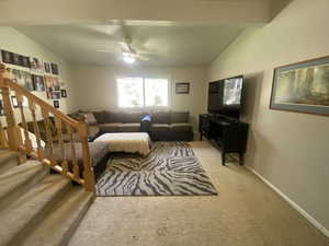 Carpeted living room with lofted ceiling and ceiling fan