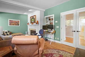 Living room with french doors, a textured ceiling, wood-type flooring, and a large fireplace