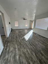 Unfurnished living room featuring a textured ceiling, dark hardwood / wood-style floors, and ceiling fan