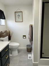 Bathroom featuring toilet, walk in shower, vanity, and tile patterned floors