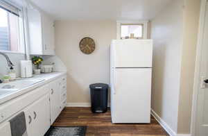 Kitchen featuring white fridge, white cabinetry, sink, and dark hardwood / wood-style floors