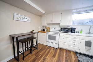 Kitchen featuring sink, electric range, white cabinetry, and dark hardwood / wood-style flooring