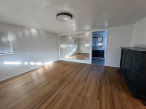 Unfurnished living room featuring a textured ceiling and dark hardwood / wood-style flooring