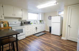 Kitchen featuring a wealth of natural light, dark wood-type flooring, sink, and white appliances