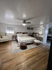 Bedroom with ceiling fan, a textured ceiling, and hardwood / wood-style floors