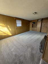 Spare room with carpet flooring, a textured ceiling, and wooden walls