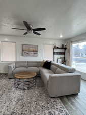 Living room featuring a textured ceiling, wood-type flooring, and ceiling fan