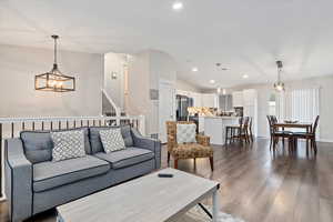 Living room with an inviting chandelier, dark hardwood / wood-style floors, and lofted ceiling