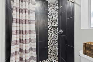 Bathroom featuring toilet and curtained shower