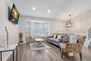 Living room with hardwood / wood-style flooring and an inviting chandelier