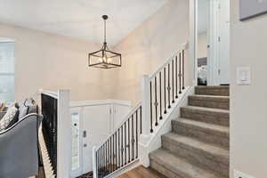 Staircase featuring hardwood / wood-style flooring and a chandelier