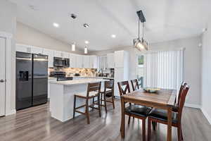 Dining area featuring sink, vaulted ceiling, and light wood-type flooring