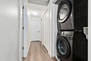 Clothes washing area featuring light hardwood / wood-style flooring and stacked washer / dryer