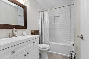 Full bathroom featuring toilet, shower / bath combo with shower curtain, vanity, and tile patterned flooring