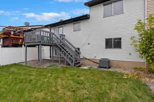 Rear view of house featuring a wooden deck, a lawn, and cooling unit