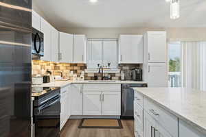 Kitchen featuring white cabinets, black appliances, sink, and dark wood-type flooring