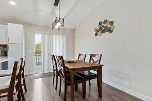 Dining room featuring lofted ceiling, dark hardwood / wood-style floors, and an inviting chandelier