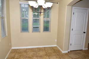 Unfurnished dining area with a chandelier and light tile patterned floors