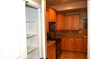 Kitchen featuring appliances with stainless steel finishes, backsplash, and light tile patterned floors