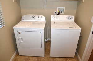 Washroom with light tile patterned flooring and washing machine and clothes dryer