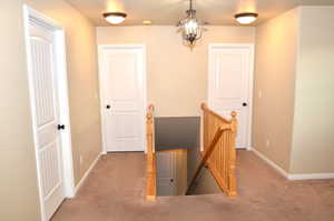 Corridor with a chandelier and light colored carpet