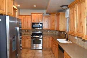 Kitchen with light tile patterned floors, tasteful backsplash, appliances with stainless steel finishes, and sink