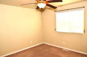 Carpeted empty room featuring ceiling fan