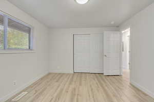 Unfurnished bedroom with light hardwood / wood-style floors and a closet