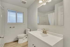 Bathroom with vanity, hardwood / wood-style floors, a shower with shower curtain, and toilet