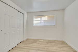 Unfurnished bedroom with light hardwood / wood-style flooring and a closet