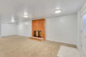 Unfurnished living room featuring light carpet and a brick fireplace